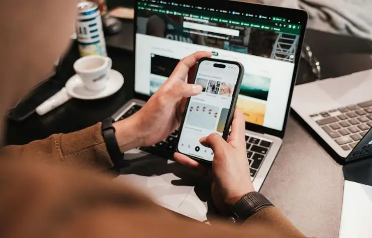 coworking una persona sentada con una laptop en una mesa y un celular en las manos