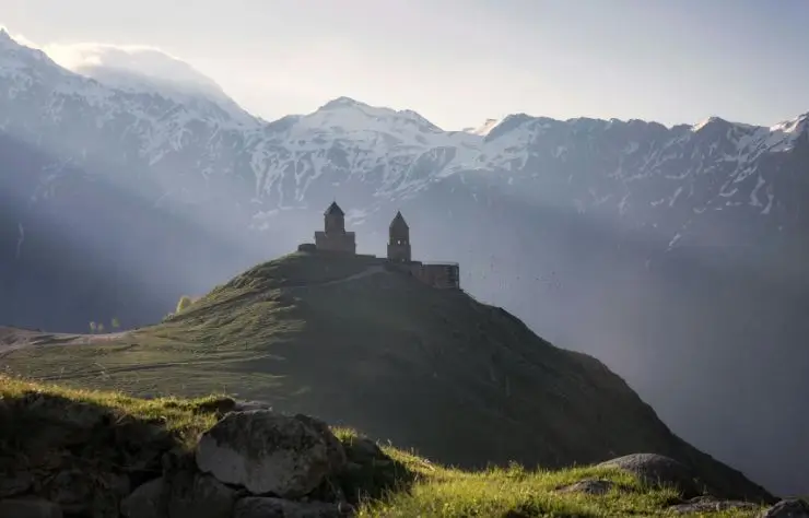 georgia Paisaje montañoso en Georgia con la iglesia de Gergeti en la cima